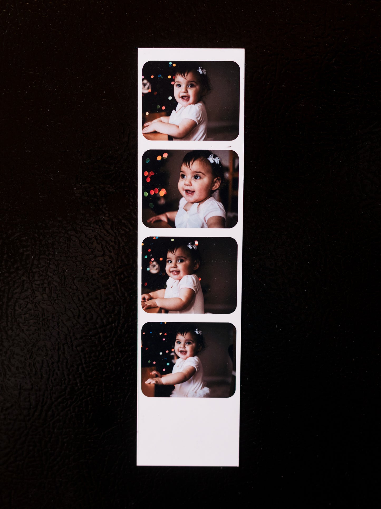 Strip of four photo prints of a child on a black background.
