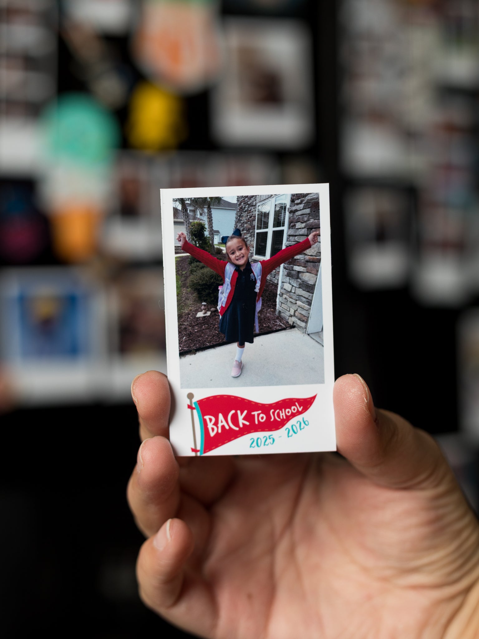 Mini instant photo style magnet with 'Back to School' text held in front of a blurred background.