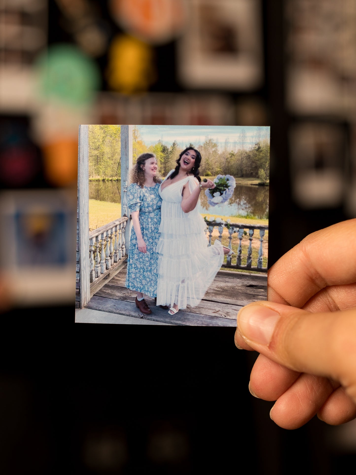 Custom square photo magnet of two women at their wedding, on a wooden bridge by a lake, with a blurred background.