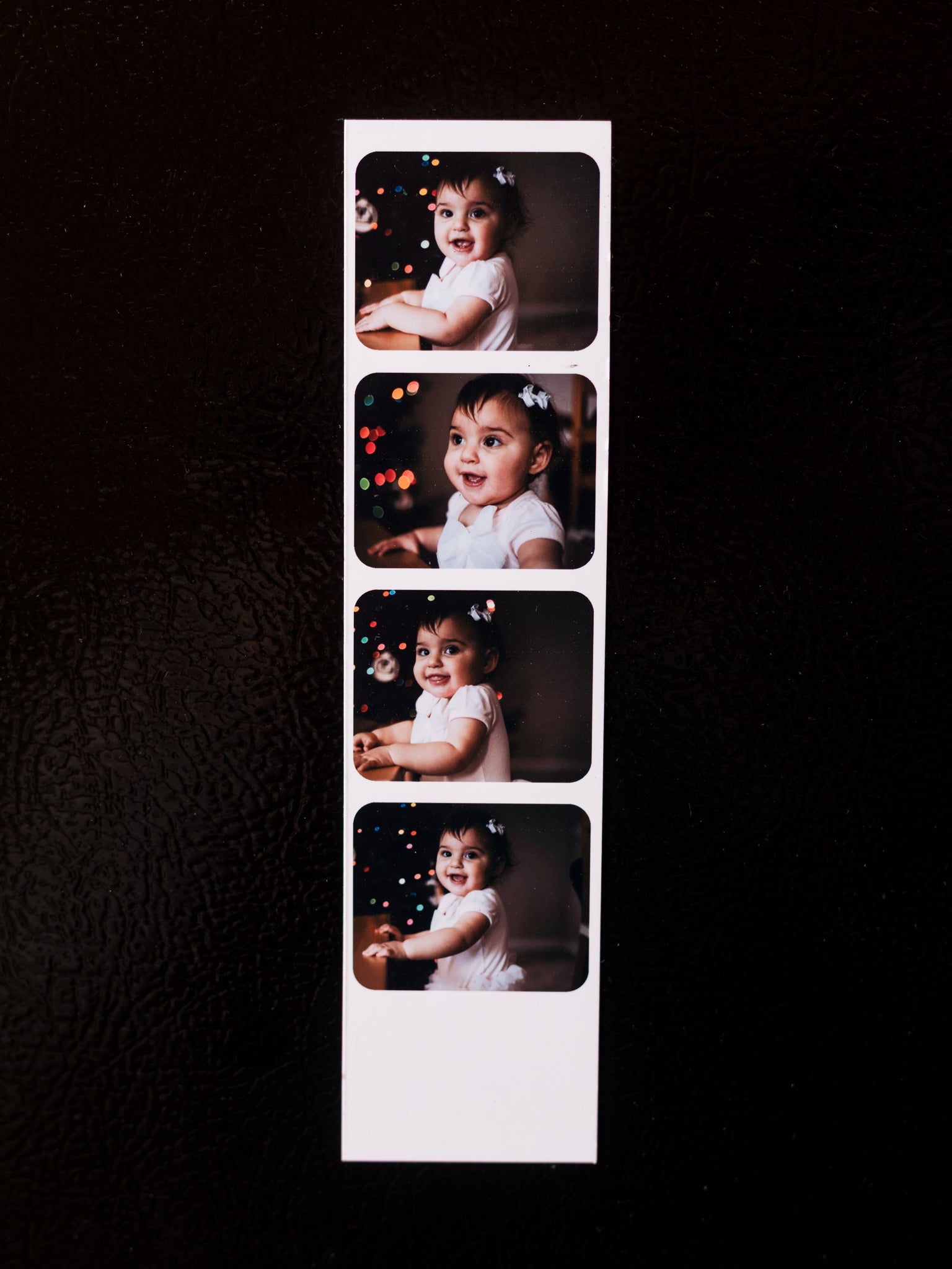 Strip of four photo prints of a child on a black background.